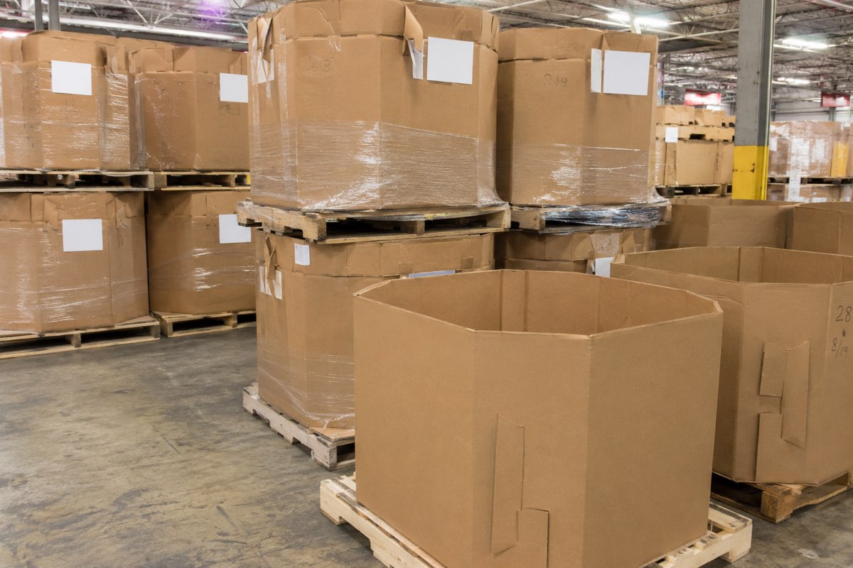 Rows of octagon bulk bins on wooden pallets inside the Houston warehouse, some shrink-wrapped and stacked two high