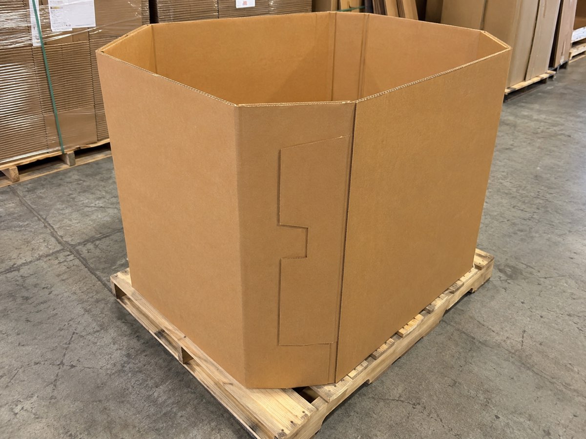 A single open octagon bulk bin standing on a wooden pallet on a warehouse floor