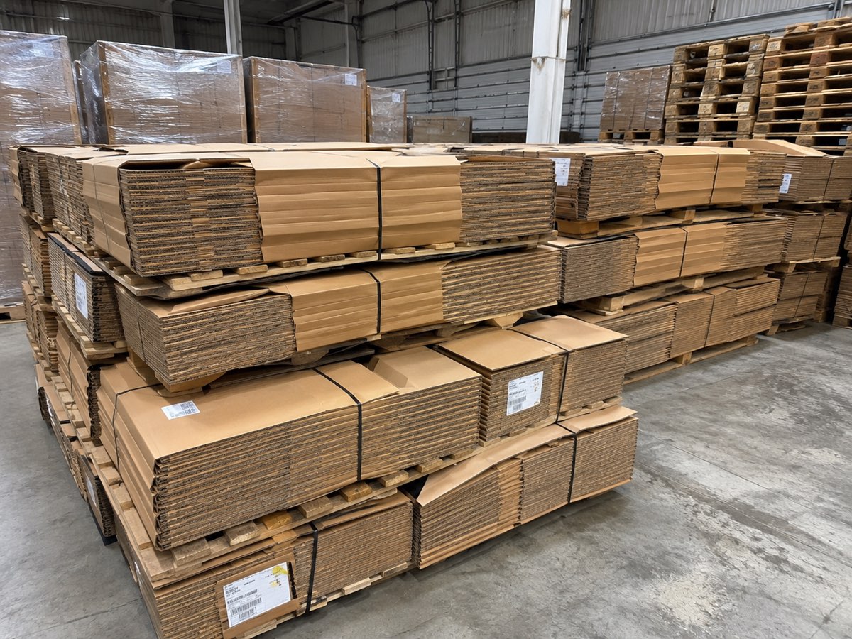 Knocked-down corrugated boxes banded into flat bundles and stacked on pallets
